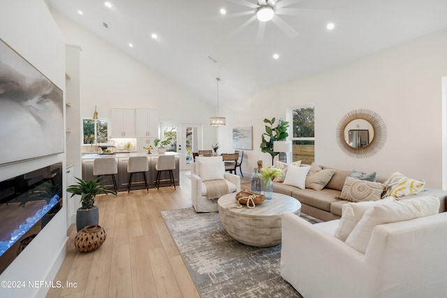 living room with french doors, high vaulted ceiling, light hardwood / wood-style flooring, and ceiling fan