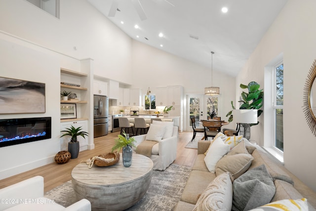 living room featuring light hardwood / wood-style floors, high vaulted ceiling, and ceiling fan