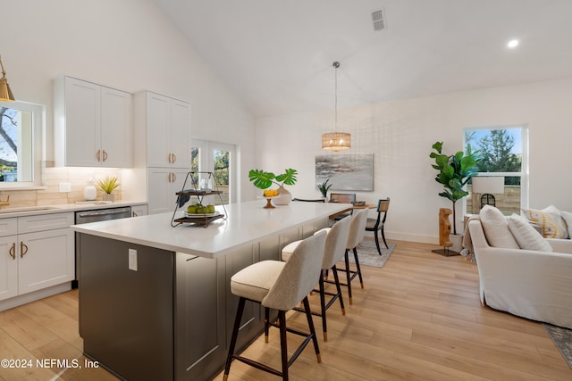 kitchen with pendant lighting, light hardwood / wood-style floors, a kitchen bar, and white cabinetry