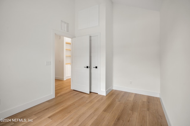 unfurnished bedroom with a high ceiling and light wood-type flooring