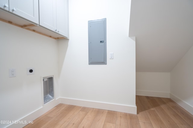 laundry area featuring electric dryer hookup, electric panel, light hardwood / wood-style flooring, and cabinets