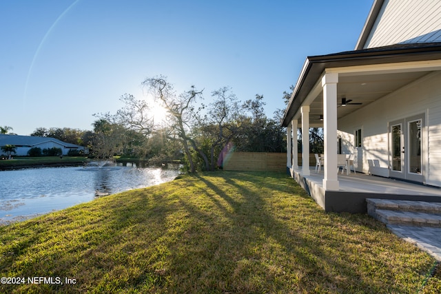 view of yard featuring a patio area, french doors, and a water view