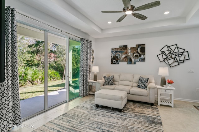 tiled living room with a tray ceiling and ceiling fan