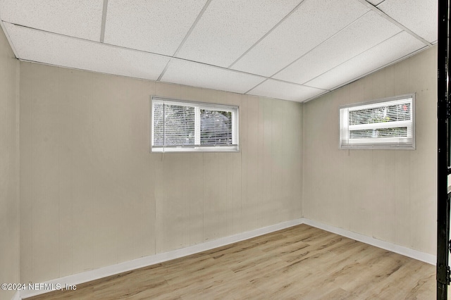 empty room featuring wood walls, a paneled ceiling, light hardwood / wood-style floors, and vaulted ceiling