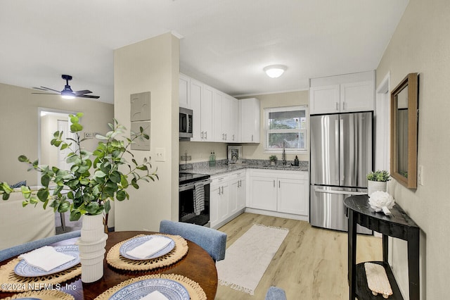 kitchen with light wood-type flooring, stainless steel appliances, ceiling fan, sink, and white cabinets