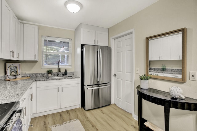 kitchen featuring appliances with stainless steel finishes, light hardwood / wood-style floors, white cabinetry, and sink