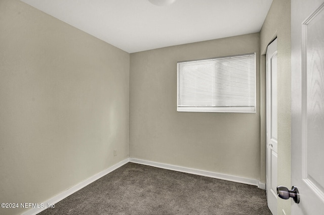 unfurnished room with dark carpet