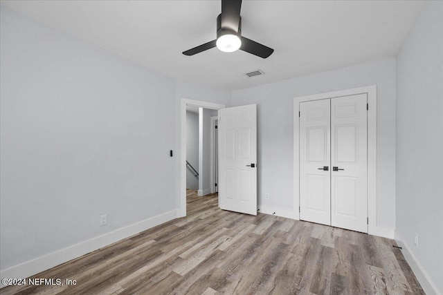 unfurnished bedroom with light hardwood / wood-style flooring, a closet, and ceiling fan