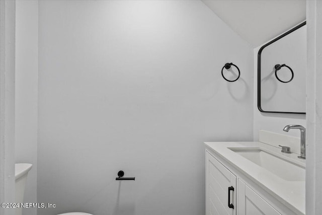 bathroom with vanity, vaulted ceiling, and toilet