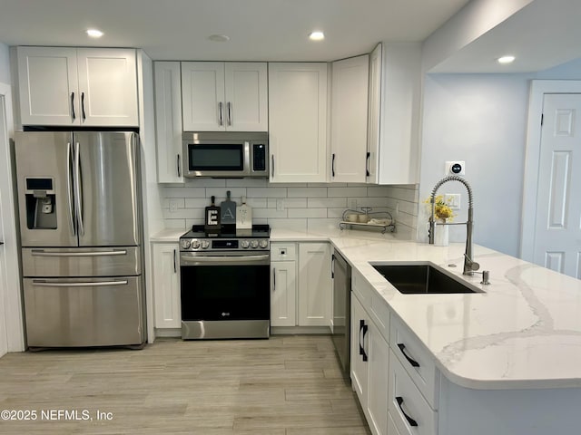 kitchen featuring sink, tasteful backsplash, stainless steel appliances, light stone countertops, and white cabinets