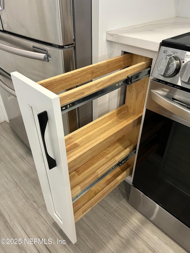 interior details featuring stainless steel range with electric stovetop and light hardwood / wood-style flooring