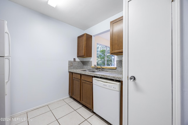 kitchen featuring light tile patterned floors, white appliances, and sink