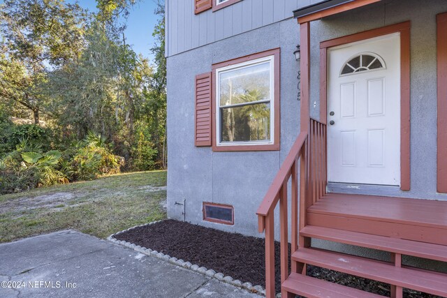 doorway to property with a lawn