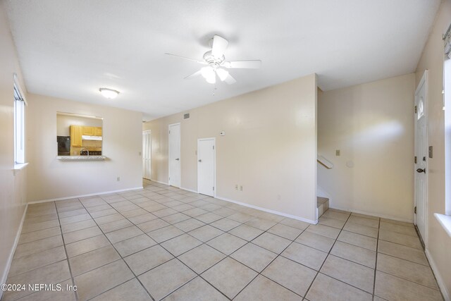 tiled spare room featuring ceiling fan