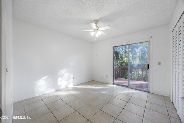 empty room featuring ceiling fan, light tile patterned flooring, and a textured ceiling