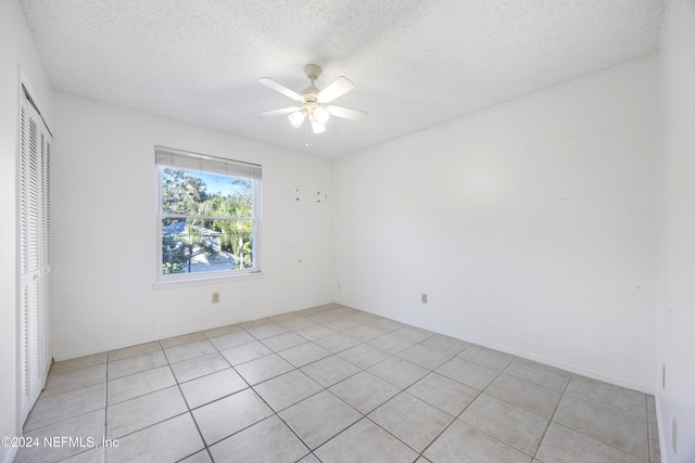 empty room with light tile patterned floors, a textured ceiling, and ceiling fan