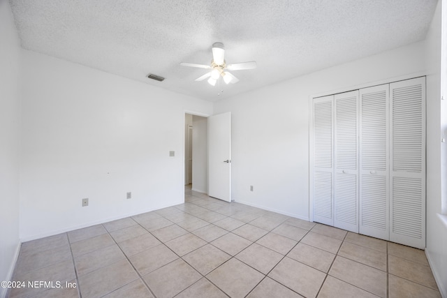 unfurnished bedroom featuring light tile patterned floors, a textured ceiling, and ceiling fan