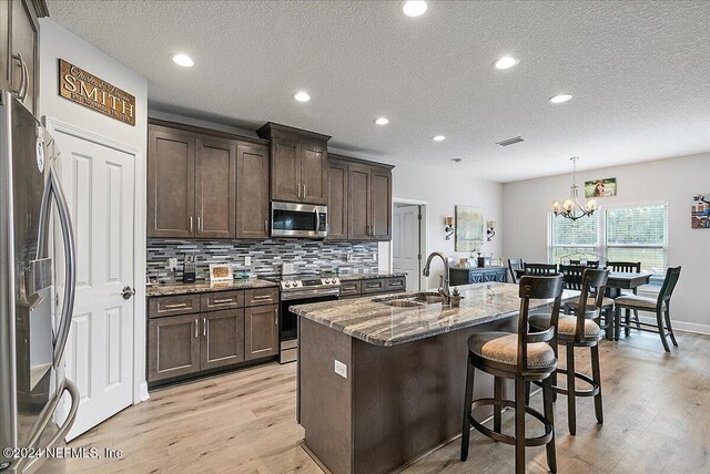 11018 Seneca Ln, Glen St Mary, FL 32040 - kitchen featuring stainless steel appliances, a sink, stone countertops, dark brown cabinetry, and light wood-style floors