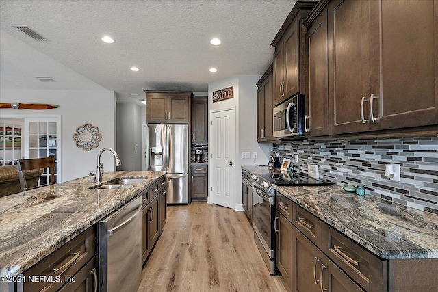 11018 Seneca Ln, Glen St Mary, FL 32040 - kitchen with appliances with stainless steel finishes, a sink, light wood-style floors, dark brown cabinetry, and dark stone countertops