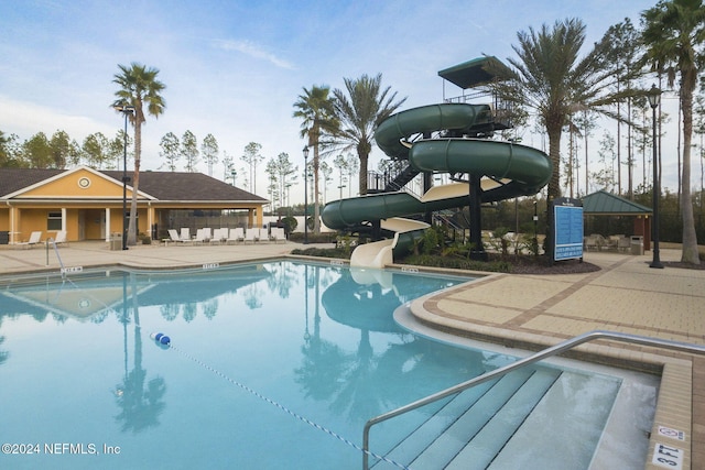 community pool featuring a patio area, a water slide, and a gazebo