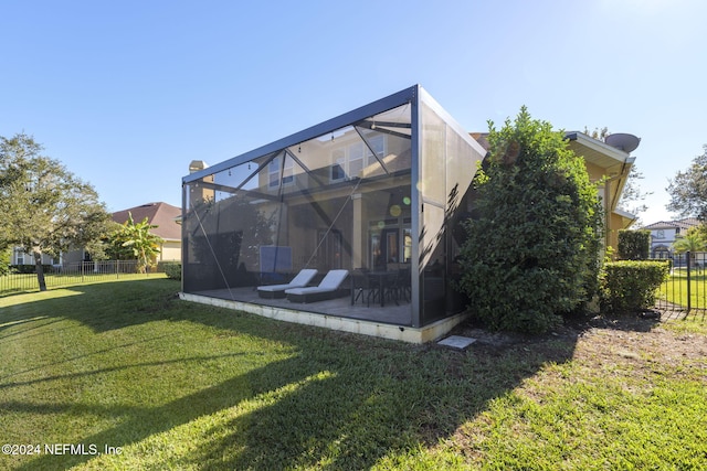 rear view of property featuring a yard, a patio area, glass enclosure, and fence