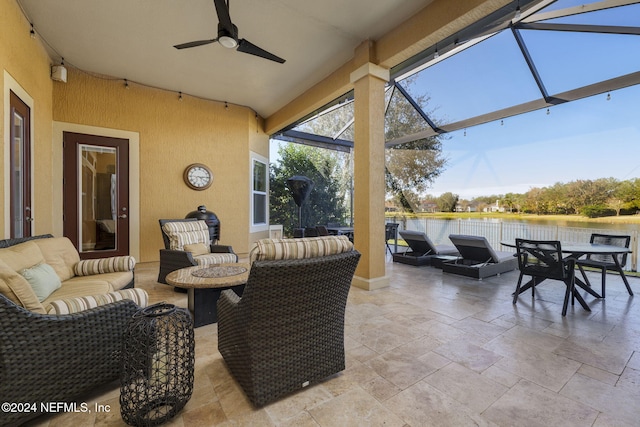 view of patio with a water view, ceiling fan, a lanai, and an outdoor living space