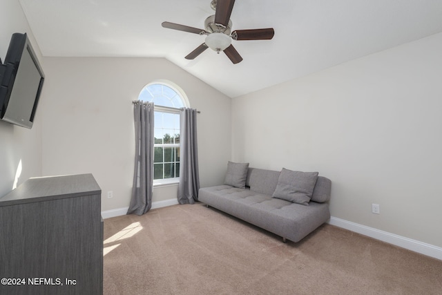 sitting room featuring light carpet, baseboards, vaulted ceiling, and a ceiling fan