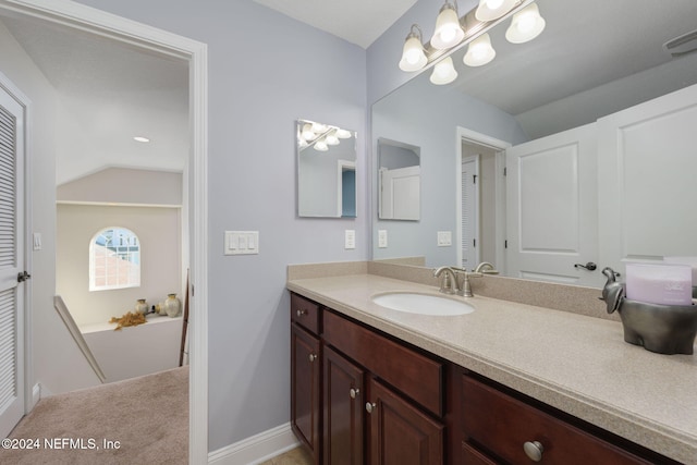 bathroom featuring lofted ceiling, visible vents, baseboards, and vanity