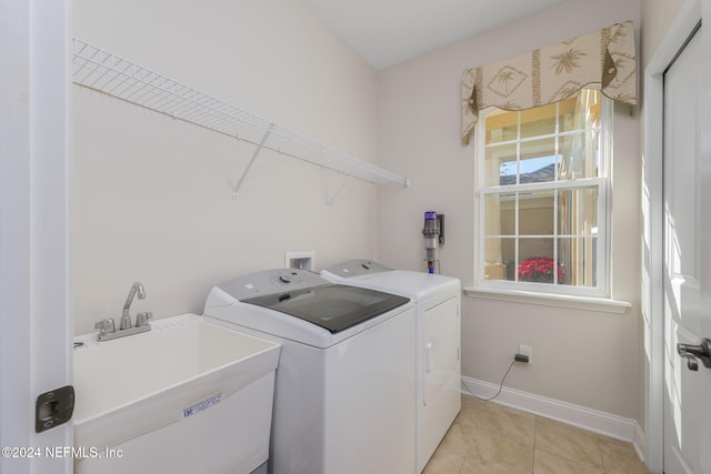 laundry area with washing machine and clothes dryer, light tile patterned floors, a sink, laundry area, and baseboards