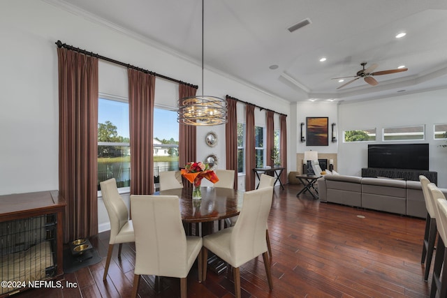 dining area with a tray ceiling, dark wood-style flooring, visible vents, and crown molding