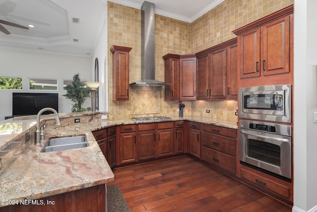 kitchen with crown molding, appliances with stainless steel finishes, a sink, wall chimney range hood, and light stone countertops