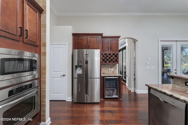 kitchen featuring beverage cooler, arched walkways, dark wood finished floors, appliances with stainless steel finishes, and light stone countertops