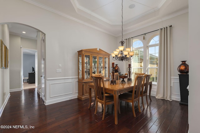 dining area with a tray ceiling, dark wood-style flooring, arched walkways, a decorative wall, and wainscoting