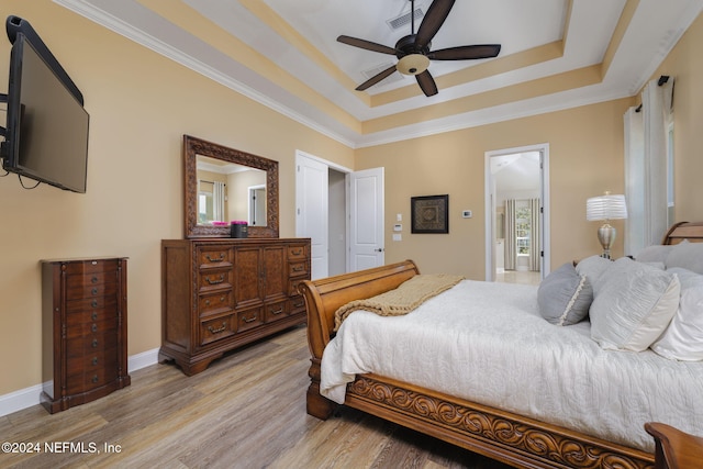 bedroom featuring light wood-type flooring, a raised ceiling, visible vents, and baseboards