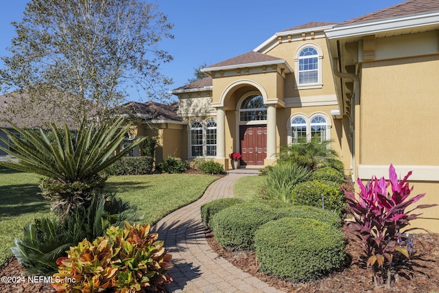 view of exterior entry with a lawn