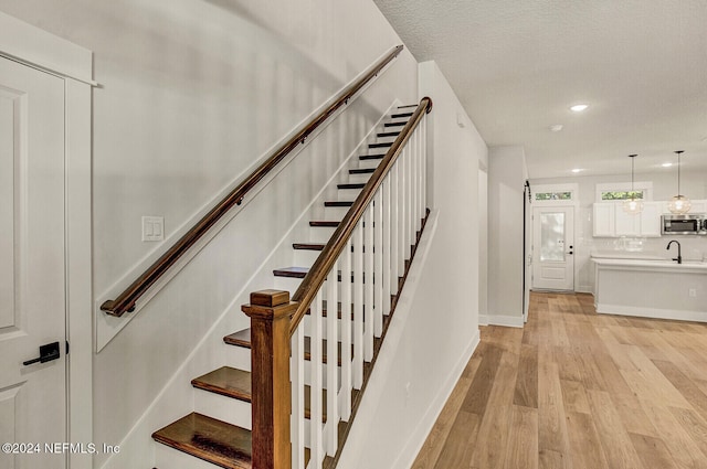 stairway featuring hardwood / wood-style floors, a textured ceiling, and sink