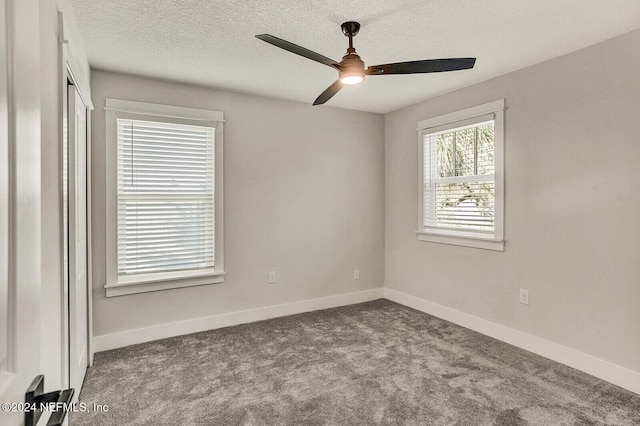 spare room with a textured ceiling, light colored carpet, and ceiling fan