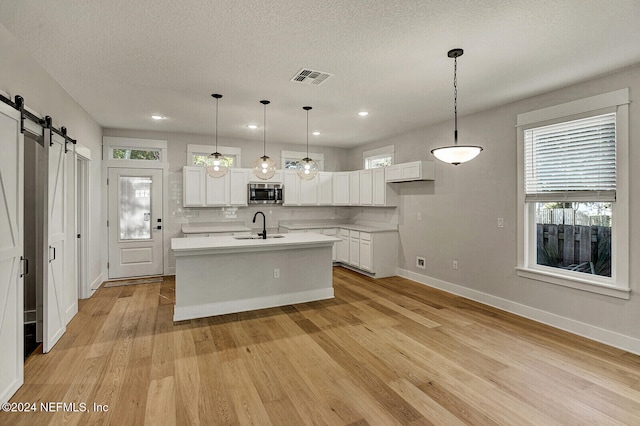 kitchen featuring white cabinetry, sink, a kitchen island with sink, and light hardwood / wood-style floors