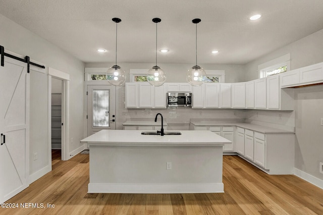 kitchen with light wood-type flooring, a barn door, and white cabinetry