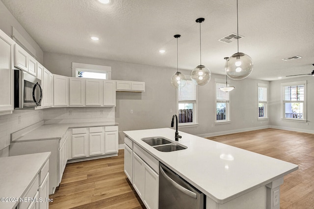 kitchen with white cabinetry, a kitchen island with sink, sink, and stainless steel appliances