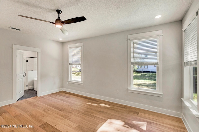 unfurnished bedroom featuring wood-type flooring, multiple windows, and ensuite bath