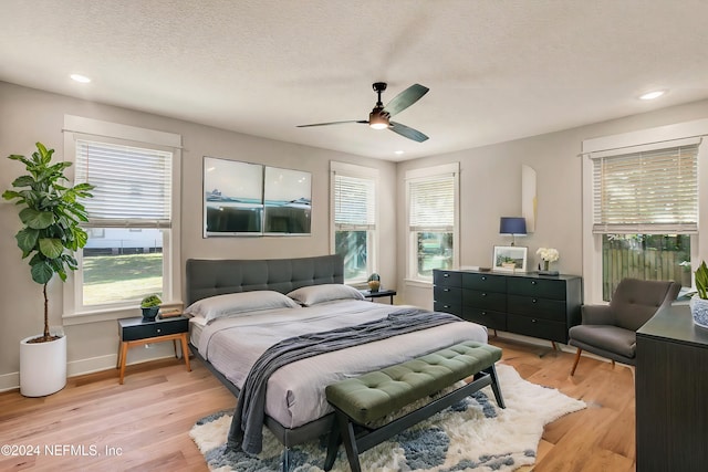 bedroom featuring a textured ceiling, light hardwood / wood-style floors, and ceiling fan