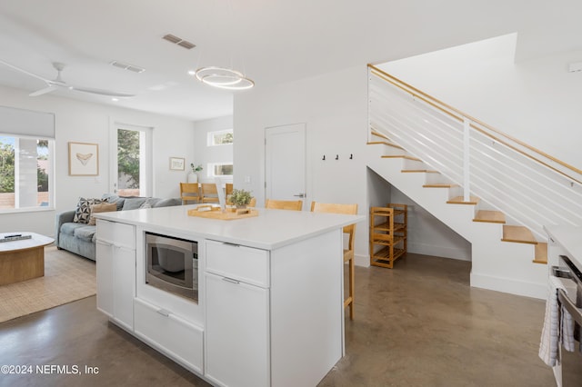 2 Sanchez Cv, Saint Augustine, FL 32080 - kitchen with stainless steel microwave, concrete floors, open floor plan, a kitchen island, and light countertops