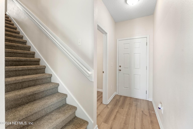 entryway featuring a textured ceiling and light hardwood / wood-style floors