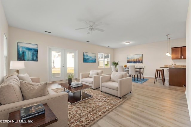 living room with ceiling fan, light wood-type flooring, a wealth of natural light, and french doors