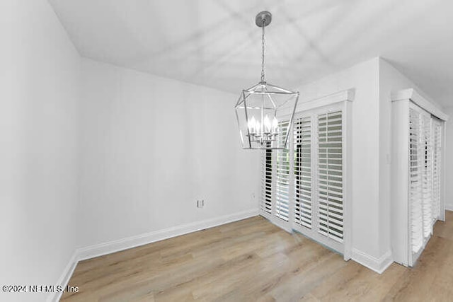 unfurnished dining area featuring an inviting chandelier and light wood-type flooring