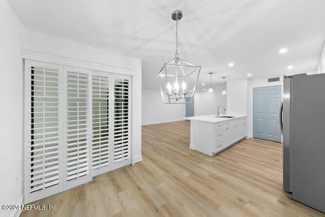 kitchen with sink, decorative light fixtures, light hardwood / wood-style floors, kitchen peninsula, and stainless steel refrigerator