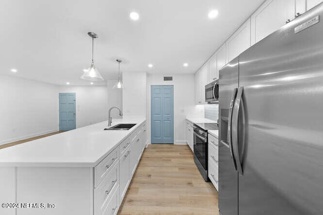 kitchen featuring white cabinetry, sink, light hardwood / wood-style flooring, decorative light fixtures, and appliances with stainless steel finishes