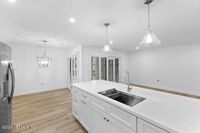 kitchen with sink, decorative light fixtures, white cabinets, stainless steel fridge with ice dispenser, and light hardwood / wood-style floors