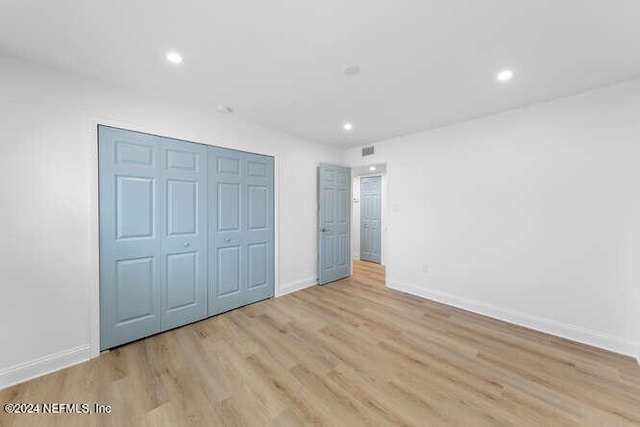 unfurnished bedroom with light wood-type flooring and a closet